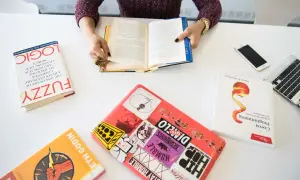 Persona leyendo libros sobre lógica, programación y desarrollo, demostrando sus competencias claves.