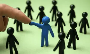 Dedo señala a figura azul entre otras negras, sugiriendo la necesidad de denunciar favoritismo laboral.
