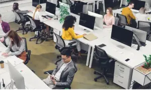 Personas trabajando en oficinas modernas, ejemplos de trabajos sedentarios.