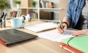 Persona concentrada en la tramitación procesal de un concurso oposición, escribiendo en documentos.