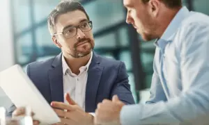 Un consultor de RRHH con gafas explica algo en una tablet a un colega.