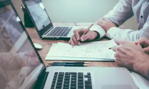 Dos personas analizan documentos y planifican, quizás sobre una nomina retribucion flexible. Laptops y bolígrafos a la vista.