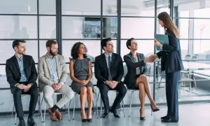 Candidatos esperan su turno para una entrevista de trabajo. Una mujer saluda a otra, un paso clave en la adaptacion laboral.