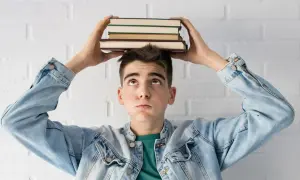 Joven con libros en la cabeza, pensando en la probabilidad de aprobar oposiciones a la primera.