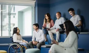Un equipo diverso colabora en una **empresa social**. Una mujer en silla de ruedas sonríe a un colega.