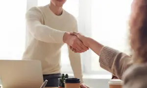 Dos personas se dan la mano, un gesto que demuestra confianza y respeto, aplicando técnicas de asertividad en un entorno de oficina.