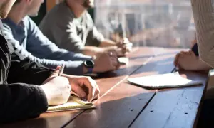 Equipo de recursos humanos de una empresa en reunión, tomando notas y discutiendo ideas.