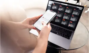Manos organizando calendarios en un teléfono y portátil. Planificar bien para que los días de reposo se pagan.