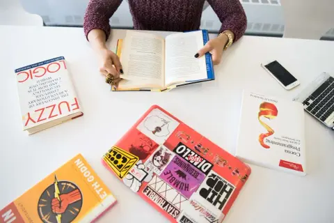 Persona leyendo libros sobre lógica, programación y desarrollo, demostrando sus competencias claves.