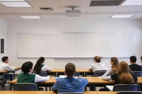 Estudiantes en clase de matemáticas, con ecuaciones en la pizarra. ¿Cuántas bolas se sacan en oposiciones de secundaria?