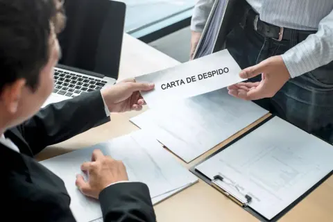 Un hombre entrega una carta de despido. El receptor, con traje, revisa documentos. Se siente la tensión de las mentiras en la carta de despido.