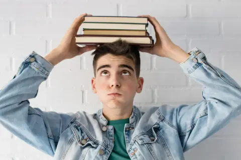 Joven con libros en la cabeza, pensando en la probabilidad de aprobar oposiciones a la primera.