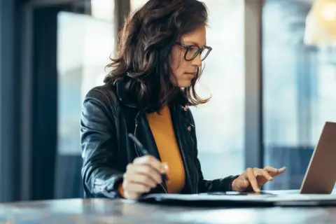 Mujer concentrada en su portátil, aprendiendo con un curso ofimática homologado.