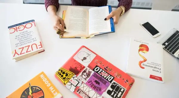 Persona leyendo libros sobre lógica, programación y desarrollo, demostrando sus competencias claves.