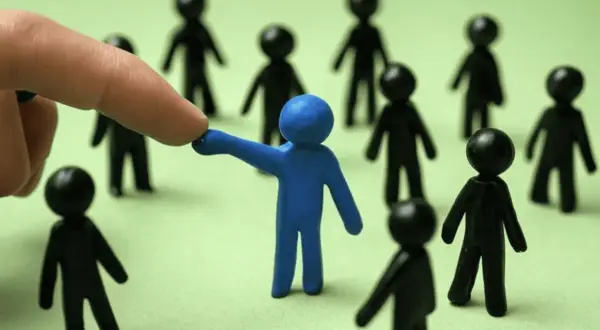 Dedo señala a figura azul entre otras negras, sugiriendo la necesidad de denunciar favoritismo laboral.