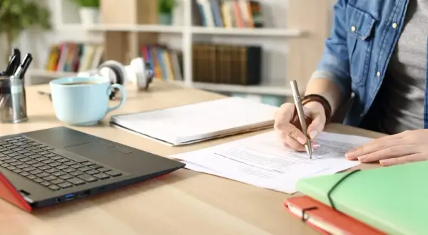 Persona concentrada en la tramitación procesal de un concurso oposición, escribiendo en documentos.