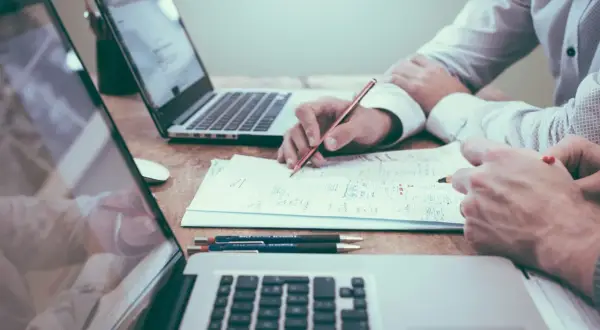 Dos personas analizan documentos y planifican, quizás sobre una nomina retribucion flexible. Laptops y bolígrafos a la vista.