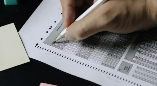 Mano completando una hoja de respuestas tipo test. ¡Descubre trucos para aprobar oposiciones tipo test y domina el examen!