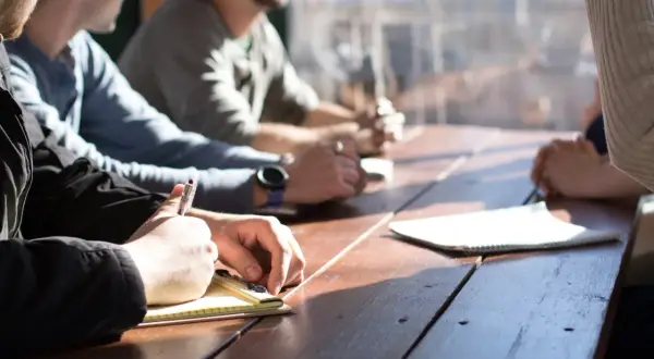 Equipo de recursos humanos de una empresa en reunión, tomando notas y discutiendo ideas.