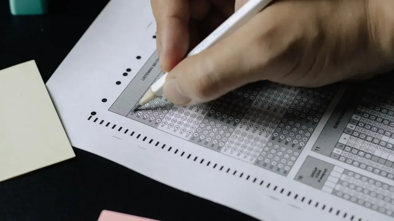 Mano completando una hoja de respuestas tipo test. ¡Descubre trucos para aprobar oposiciones tipo test y domina el examen!