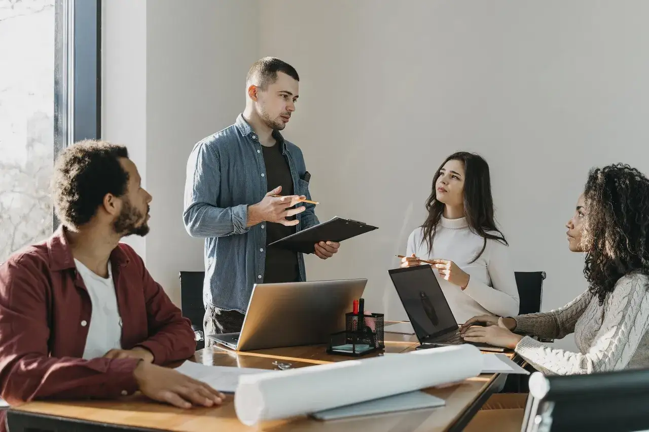 Equipo diverso practicando la escucha activa en el trabajo. Un hombre presenta ideas mientras los dem&aacute;s escuchan atentamente.