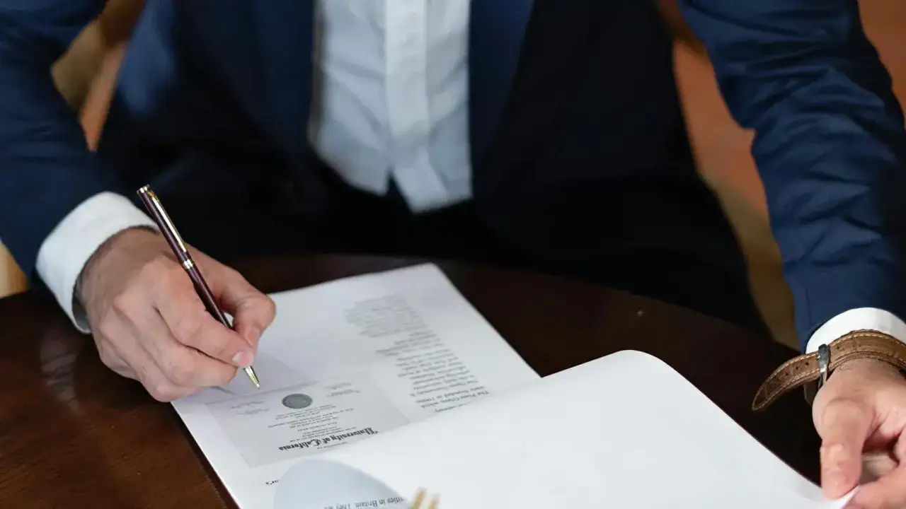 Persona firma un documento, quiz&aacute;s un contrato temporal indefinido, con un bol&iacute;grafo de oro.