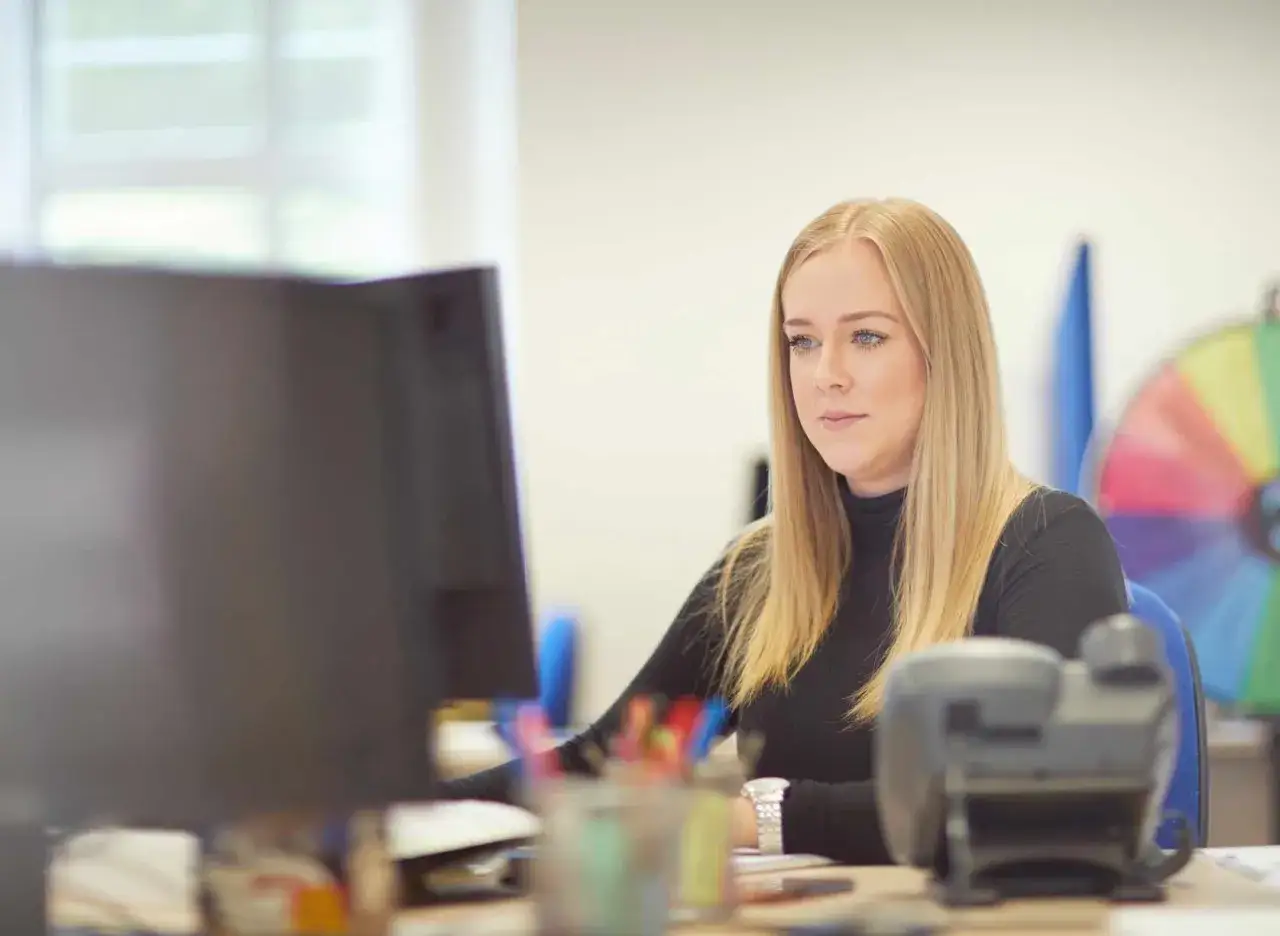 Mujer rubia trabajando en su ordenador, un ejemplo de microempresa definición en acción.