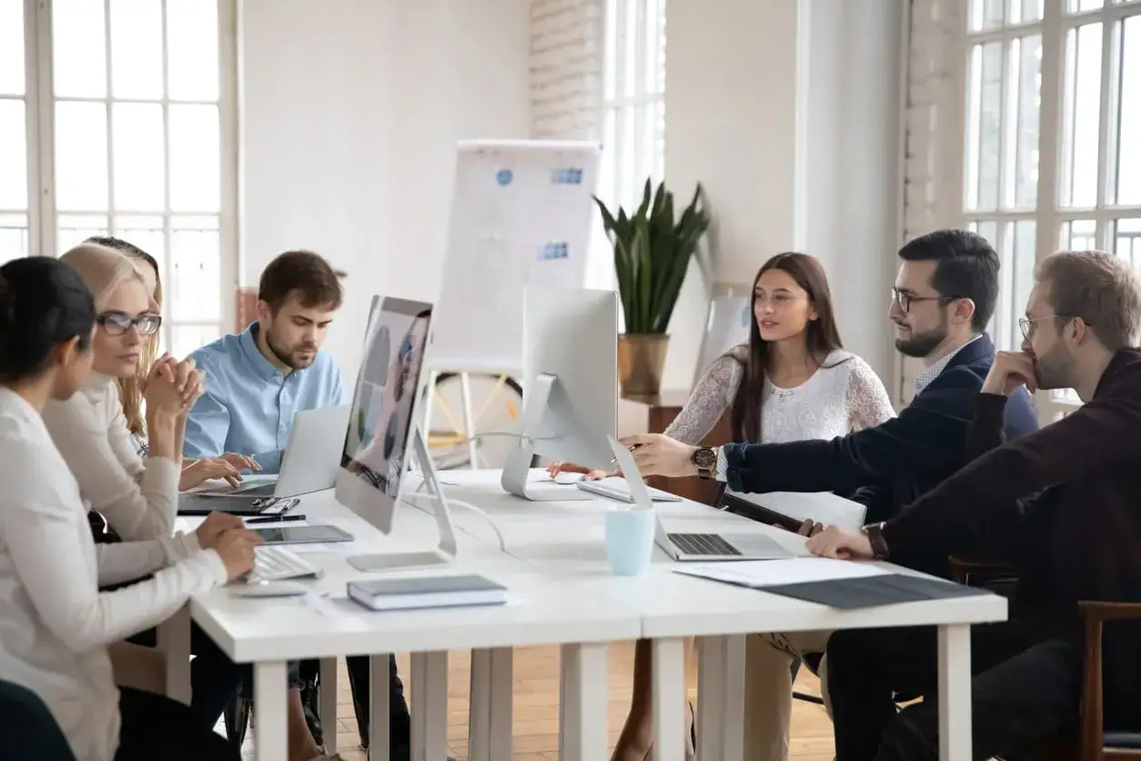 Equipo colaborando en una reuni&oacute;n, aplicando t&eacute;cnicas de asertividad para expresar ideas y resolver problemas.