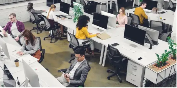 Personas trabajando en oficinas modernas, ejemplos de trabajos sedentarios.