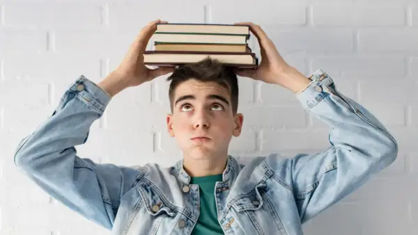 Joven con libros en la cabeza, pensando en la probabilidad de aprobar oposiciones a la primera.